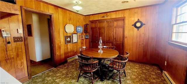 dining area with a healthy amount of sunlight, wooden walls, and baseboard heating