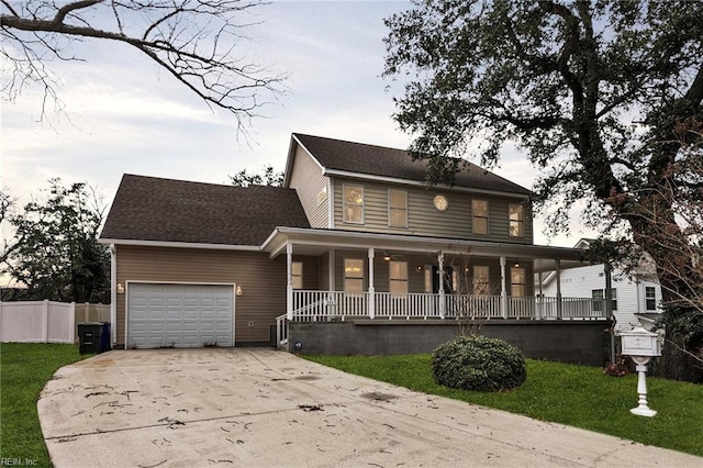 view of front of home featuring a garage, a front yard, and covered porch