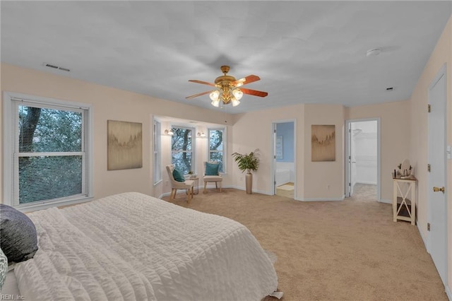 carpeted bedroom featuring multiple windows, a walk in closet, ceiling fan, and ensuite bathroom