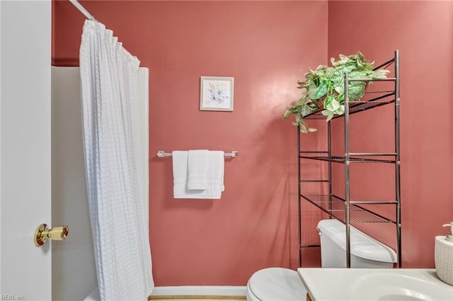 bathroom featuring a shower with curtain and toilet