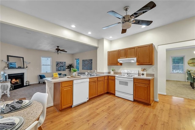 kitchen with sink, white appliances, light hardwood / wood-style flooring, ceiling fan, and kitchen peninsula