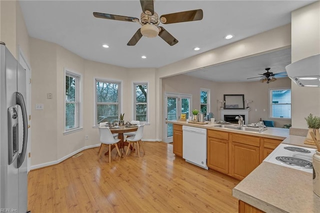 kitchen with light brown cabinetry, sink, stainless steel fridge, white dishwasher, and light hardwood / wood-style floors