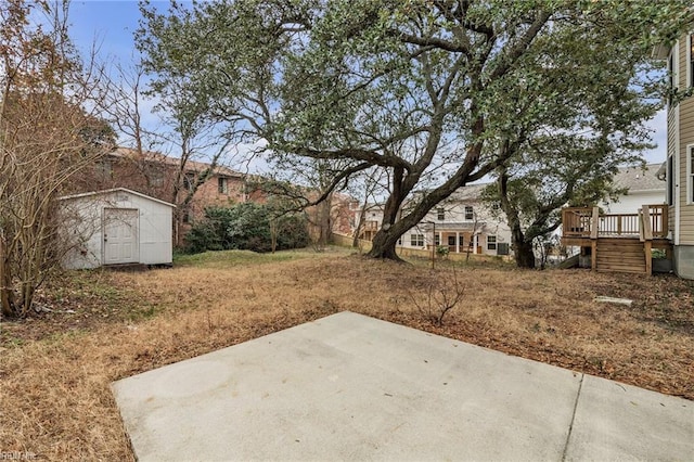 view of yard with a wooden deck, a shed, and a patio area