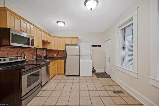 kitchen featuring stacked washer and dryer, appliances with stainless steel finishes, and light brown cabinetry