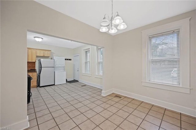 unfurnished dining area featuring a healthy amount of sunlight, light tile patterned floors, and a chandelier