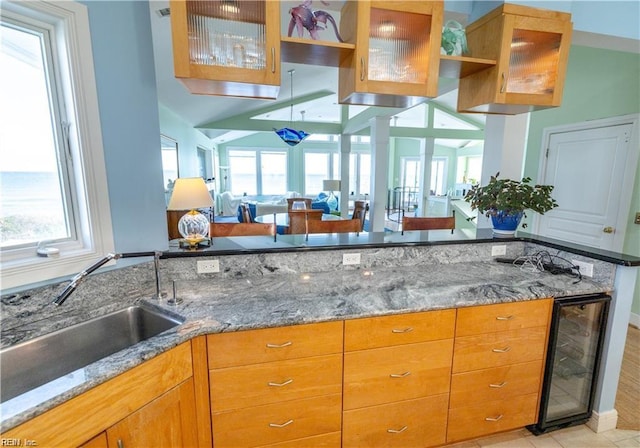 kitchen featuring plenty of natural light, sink, beverage cooler, and light stone counters