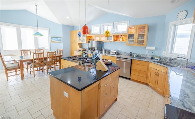 kitchen featuring pendant lighting, sink, appliances with stainless steel finishes, a kitchen island, and dark stone counters