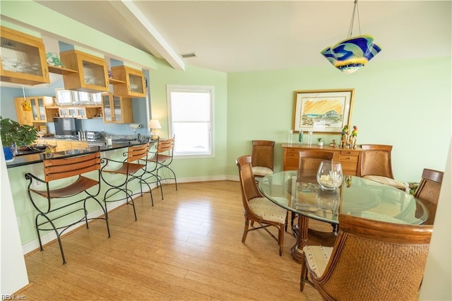 dining space featuring light hardwood / wood-style floors and beamed ceiling