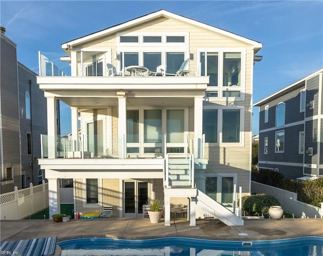 back of house featuring a balcony, a fenced in pool, and a patio