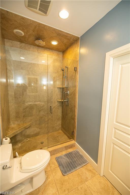 bathroom with tile patterned flooring, a shower with door, and toilet