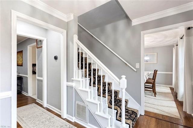 stairway featuring ornamental molding and hardwood / wood-style floors