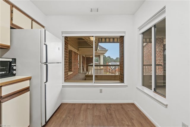 kitchen with white cabinetry, white fridge, and light hardwood / wood-style floors