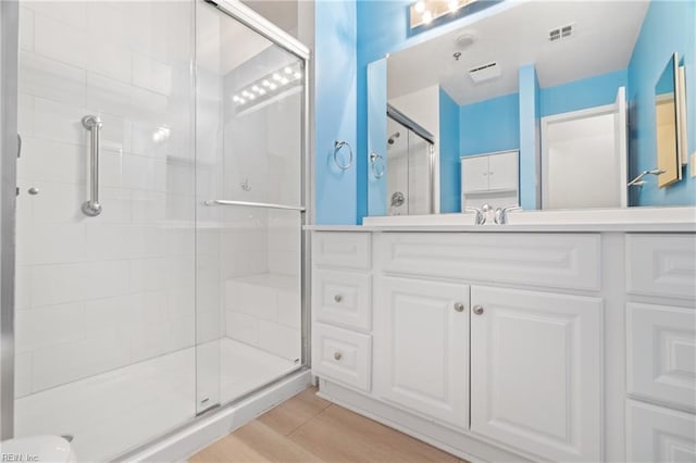 bathroom with vanity, a shower with shower door, and wood-type flooring