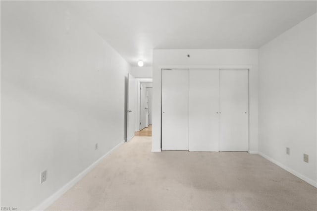 unfurnished bedroom with light carpet and a closet