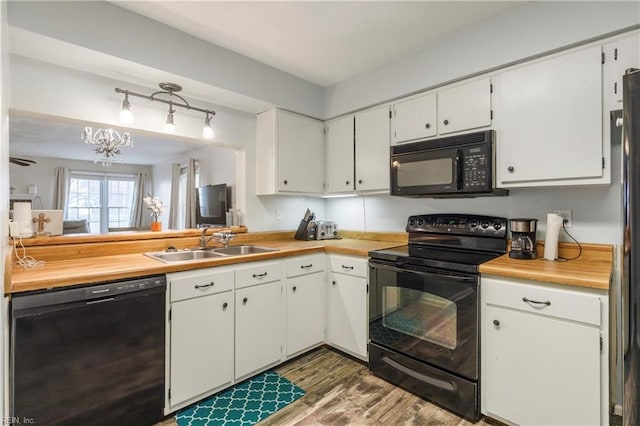 kitchen with dark hardwood / wood-style flooring, sink, black appliances, and white cabinets