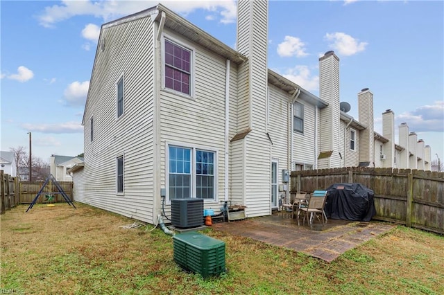 back of house with central AC, a playground, a patio, and a lawn