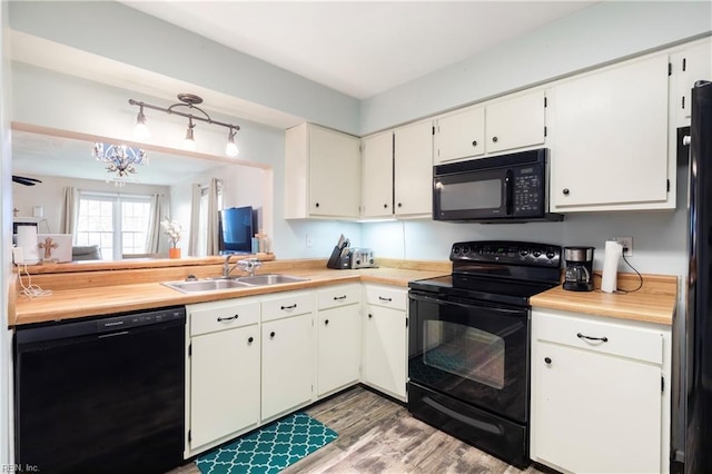 kitchen with sink, hardwood / wood-style flooring, black appliances, and white cabinets