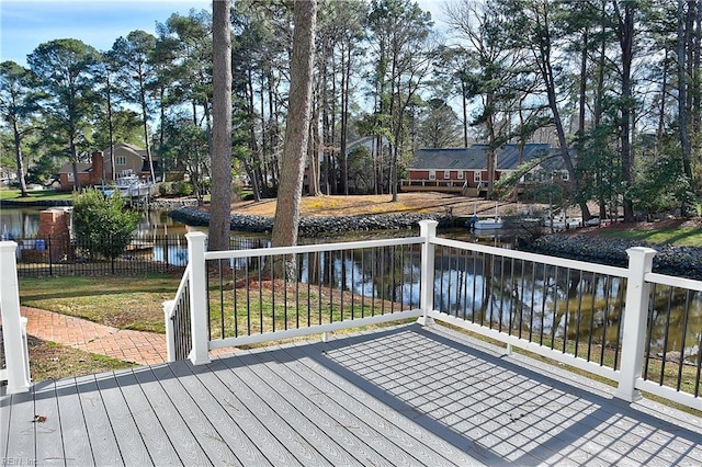 wooden terrace with a water view and a lawn