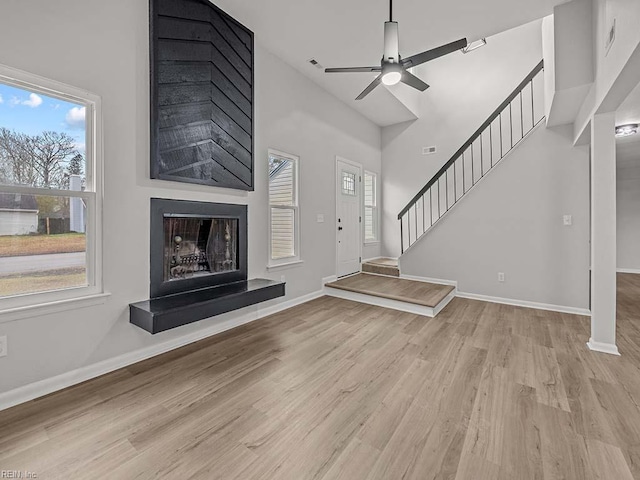 unfurnished living room featuring a fireplace, light hardwood / wood-style floors, and ceiling fan