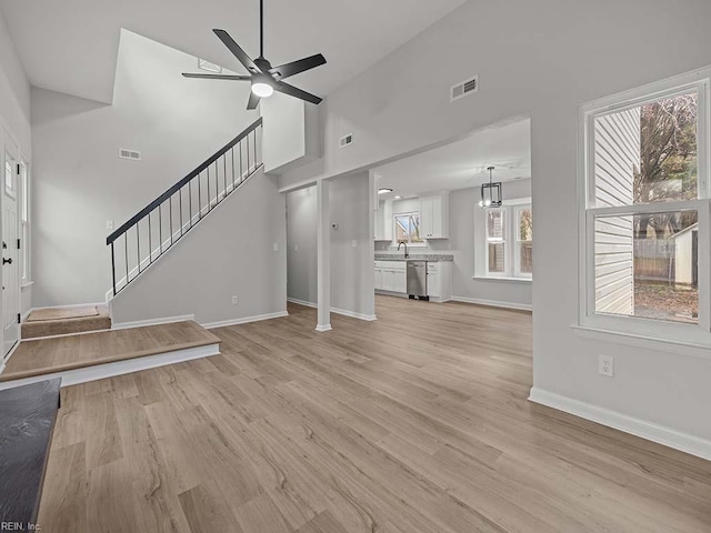 unfurnished living room featuring high vaulted ceiling, sink, ceiling fan, and light hardwood / wood-style flooring