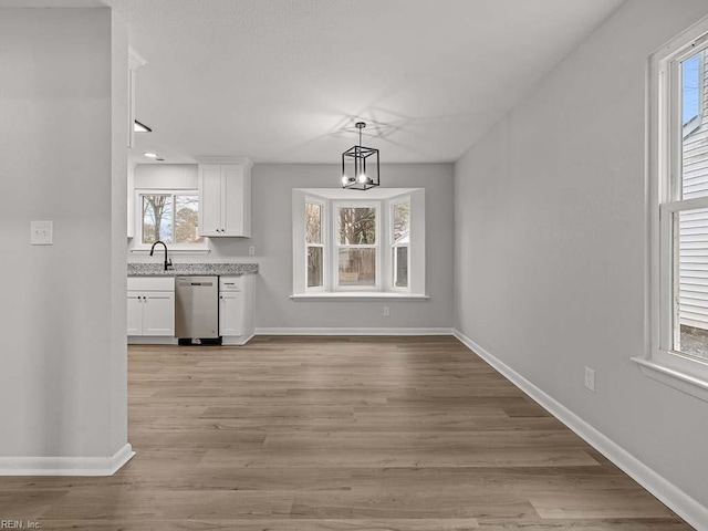 unfurnished dining area with a chandelier, sink, and light hardwood / wood-style flooring