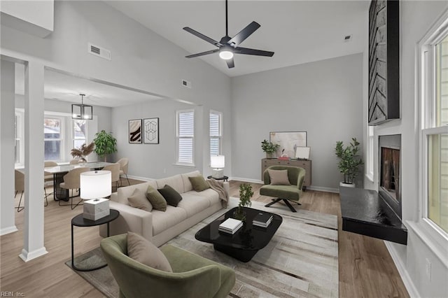 living room featuring a chandelier, high vaulted ceiling, and light hardwood / wood-style flooring