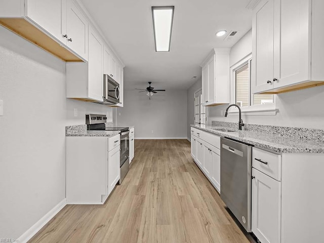 kitchen featuring light stone countertops, appliances with stainless steel finishes, sink, and white cabinets