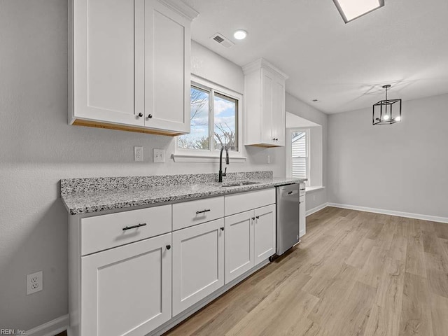 kitchen featuring light stone counters, light hardwood / wood-style flooring, stainless steel dishwasher, pendant lighting, and white cabinets