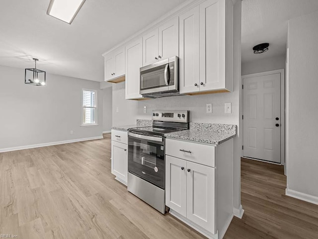 kitchen with white cabinetry, stainless steel appliances, light stone countertops, and pendant lighting