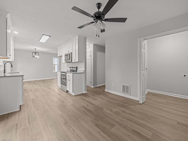 kitchen featuring sink, white cabinets, hanging light fixtures, stainless steel appliances, and light hardwood / wood-style flooring