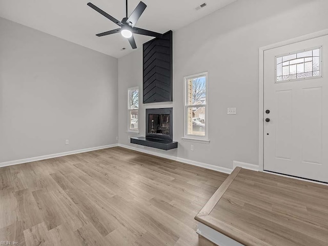 unfurnished living room featuring a fireplace, light hardwood / wood-style floors, and plenty of natural light