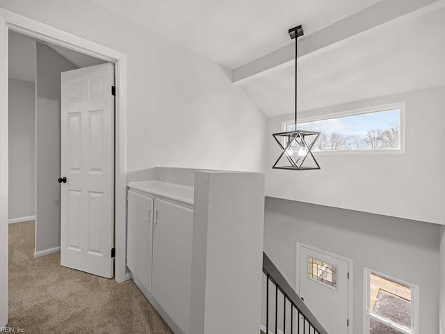 hallway featuring vaulted ceiling with beams, a notable chandelier, and light colored carpet