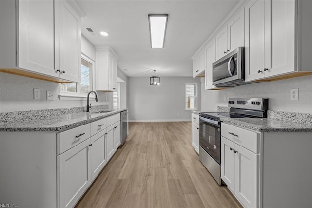 kitchen featuring light stone counters, appliances with stainless steel finishes, decorative light fixtures, and white cabinets