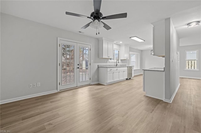 unfurnished living room with sink, light hardwood / wood-style floors, french doors, and ceiling fan