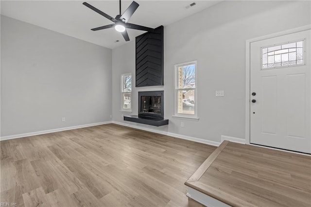 unfurnished living room with a large fireplace, ceiling fan, and light hardwood / wood-style flooring