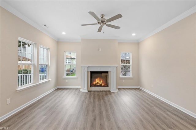 unfurnished living room featuring a wealth of natural light, ornamental molding, and light hardwood / wood-style floors