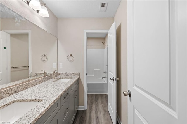 bathroom featuring hardwood / wood-style flooring, vanity, and bathing tub / shower combination