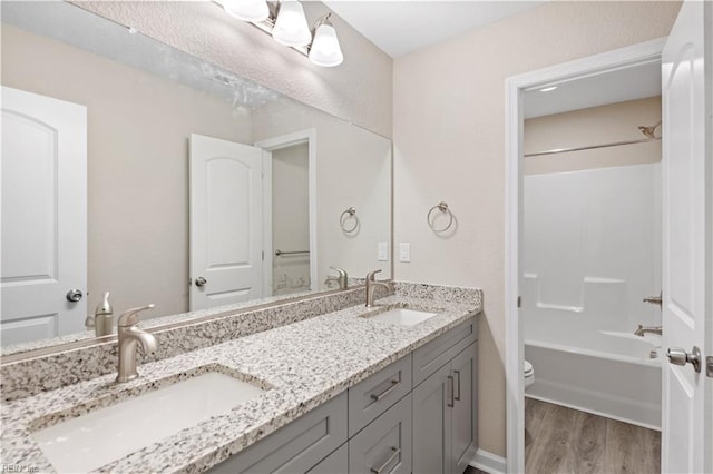 full bathroom with wood-type flooring, vanity, shower / bathtub combination, and toilet