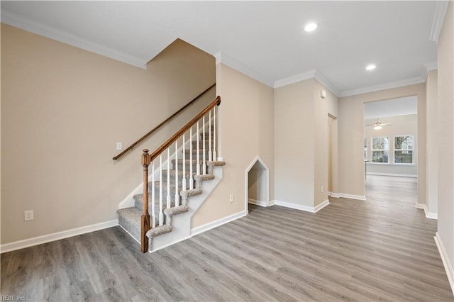 stairway with hardwood / wood-style floors, ornamental molding, and ceiling fan