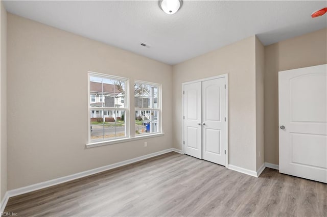 unfurnished bedroom with light wood-type flooring and a closet