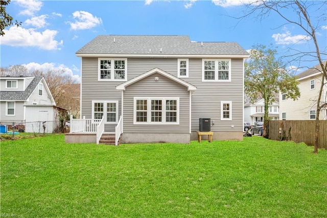 back of property with central AC unit, a deck, and a lawn