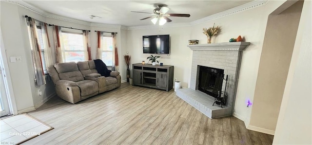 living room with a fireplace, ornamental molding, light wood-type flooring, and ceiling fan