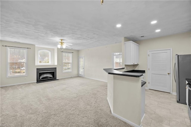 kitchen with ceiling fan, stainless steel appliances, a wealth of natural light, white cabinets, and light colored carpet