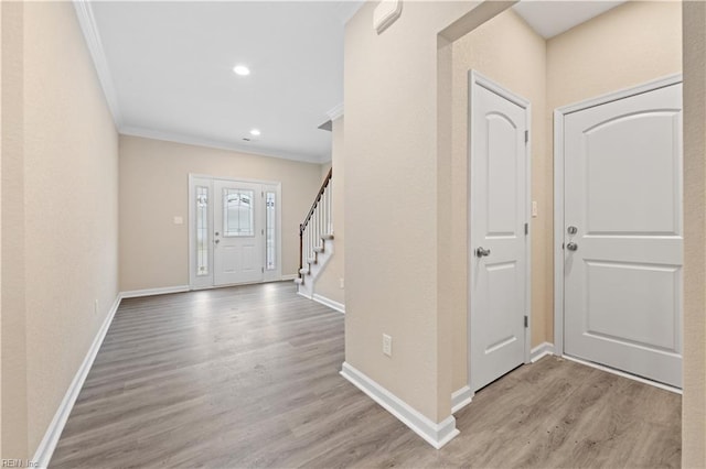 foyer entrance with crown molding and light wood-type flooring