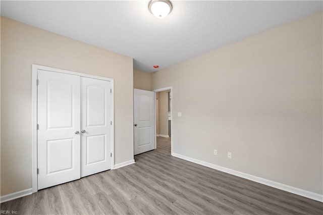 unfurnished bedroom with light wood-type flooring and a closet