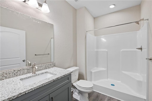 bathroom featuring a shower, wood-type flooring, vanity, and toilet