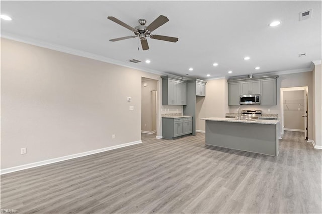 kitchen featuring gray cabinets, light stone counters, stainless steel appliances, crown molding, and light wood-type flooring