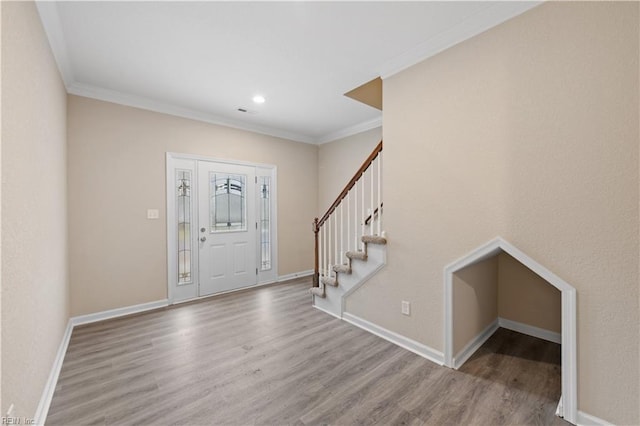 entryway with ornamental molding and light hardwood / wood-style flooring