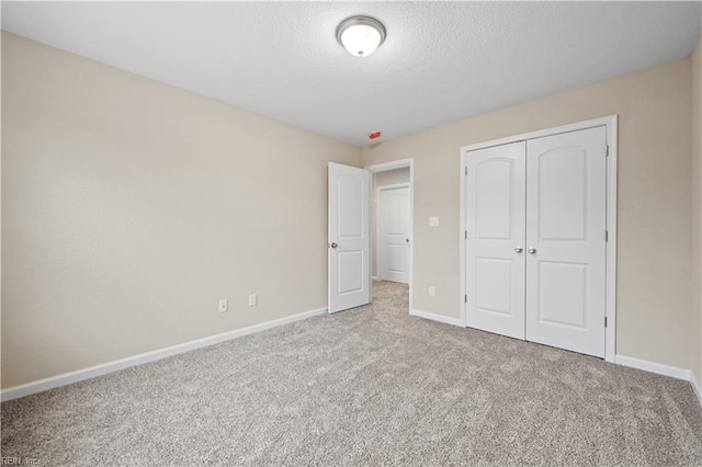 unfurnished bedroom with a closet, light carpet, and a textured ceiling