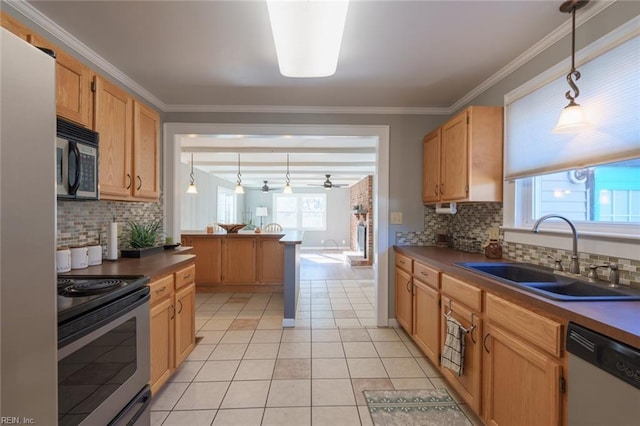 kitchen featuring sink, crown molding, light tile patterned floors, appliances with stainless steel finishes, and hanging light fixtures